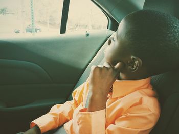 Boy with hand on chin sitting in car