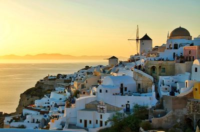 High angle view of buildings by sea against sky during sunset