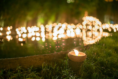 Close-up of illuminated diya on field at night