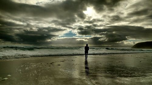 Silhouette man standing on beach against sky during sunset