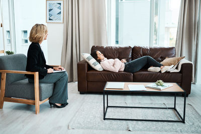 Psychiatrist looking at patient lying on sofa