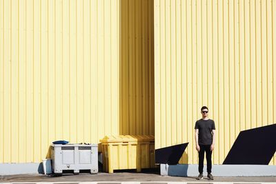 Full length of man standing against yellow cargo container