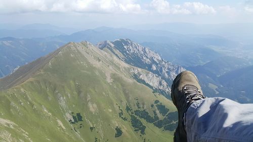 Low section of person on mountain against sky