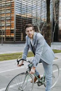 Businessman with bicycle standing on footpath in city