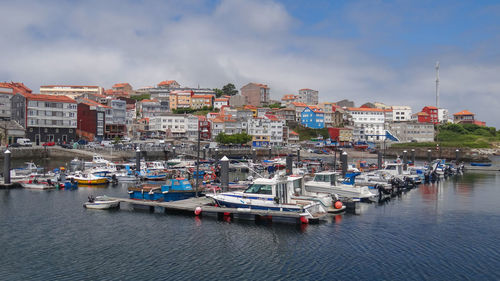 Boats moored at harbor against buildings in city