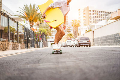 Low section of man skateboarding on street in city