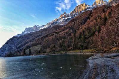 Scenic view of lake by mountains against sky