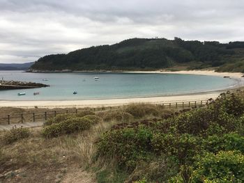 Scenic view of calm beach against cloudy sky