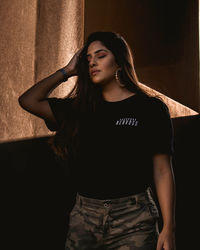 Young woman standing against wall sun light long hair