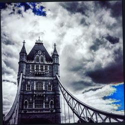 Low angle view of suspension bridge against cloudy sky