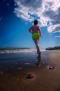 Full length rear view of shirtless boy on beach