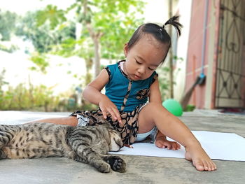 Full length of girl playing with cat at home