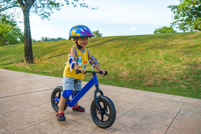 Smiling cute boy riding bicycle on footpath at park