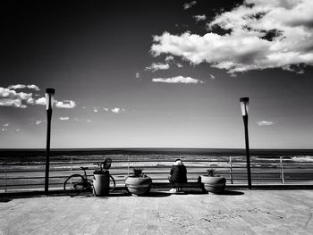 People sitting by sea against sky