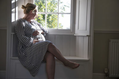 Woman looking through window at home