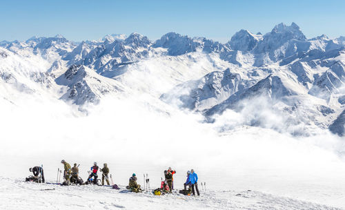 Group of people on snowcapped mountain against sky