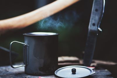 Close-up of mug by knife on wood