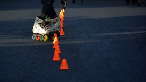 Low section of person roller skating by traffic cones on road