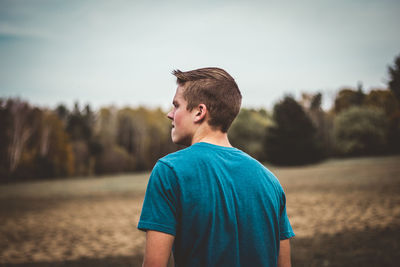 Rear view of young man standing against trees