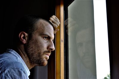 Portrait of young man looking through window