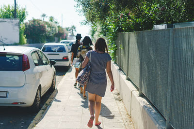 Rear view of women walking on footpath in city