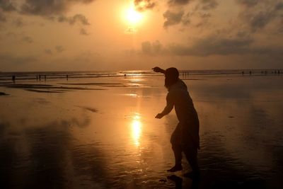 Boy on beach against sky during sunset