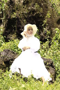 Full length of woman with white flowers on field