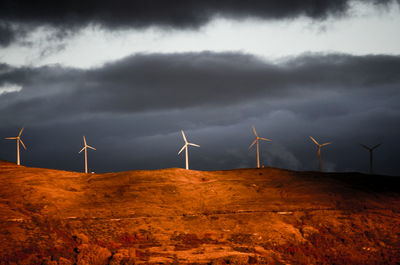 Windmills on field against sky