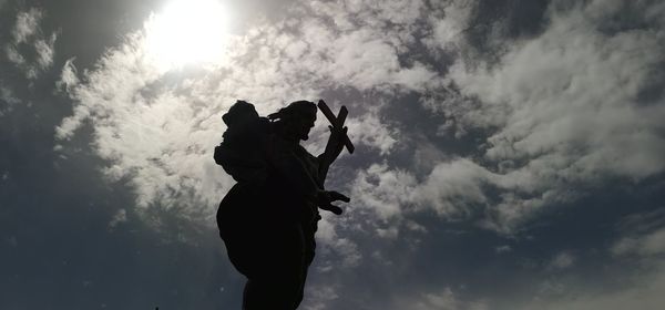 Low angle view of silhouette woman standing against sky