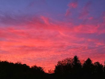 Low angle view of silhouette trees against dramatic sky