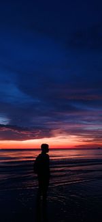 Silhouette man standing on beach against sky during sunset