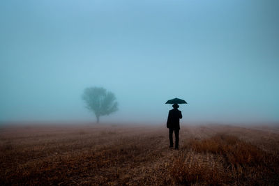 Man walking with an umbrella in fog