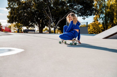 Cheerful caucasian woman with blonde hair skating in urban setting