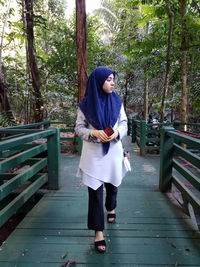 Full length of young woman standing against trees