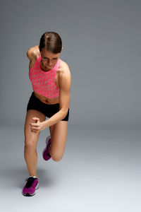 Side view of young woman exercising against white background