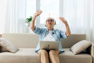 Young woman using laptop while sitting on sofa at home