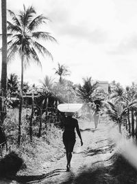 Rear view of woman walking on beach against sky