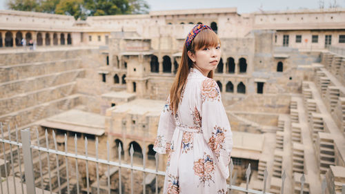 Portrait of woman standing against historic building