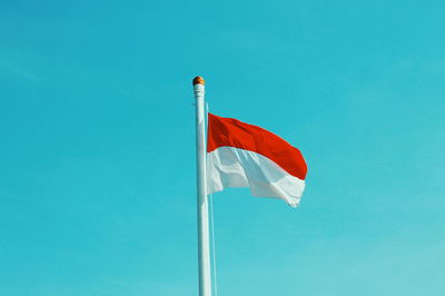 Low angle view of flag against blue sky