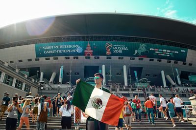 Young man with mexican flag standing outside stadium