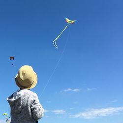 Rear view of person flying kite in blue sky