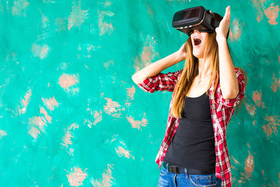 Woman wearing sunglasses standing against wall