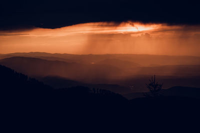 Scenic view of silhouette mountains against orange sky