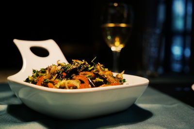 Close-up of vegetarian food in bowl on table with drink glass in background
