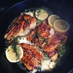 Close-up of fish cooking in pot with herbs and lemon