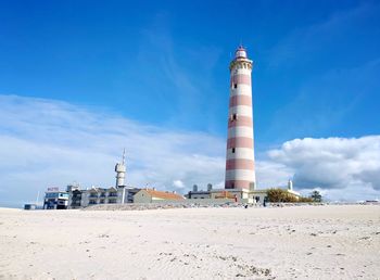 Lighthouse on beach against sky