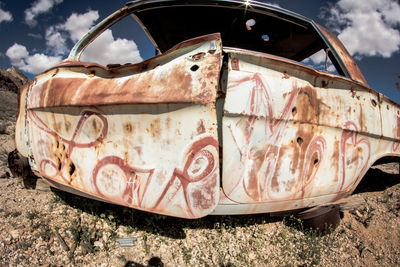 Damaged car on field against sky