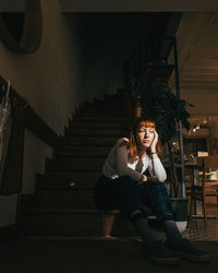 Sad young woman sitting on staircase