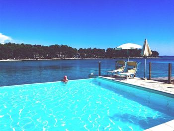 Swimming pool in sea against clear blue sky