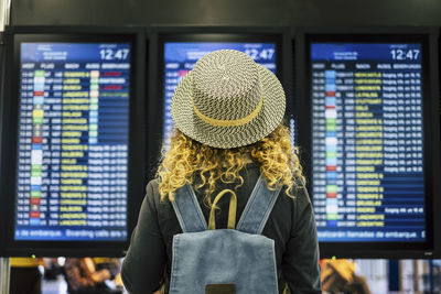 Rear view of woman wearing hat while standing at airport